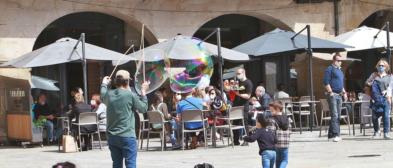 Vista parcial de las terrazas de Plaza Mayor a mediodía de ayer, animada por un artista ambulante haciendo pompas de jabón. |   // IÑAKI OSORIO