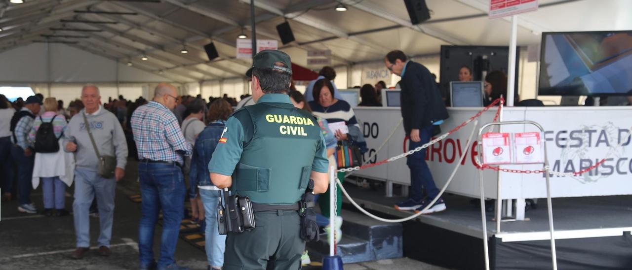 Un agente de la Guardia Civil y los puestos de expedición de tickets, en la Festa do Marisco de 2019.