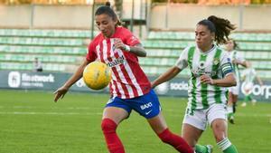 Nana, del Betis, disputa el balón ante Sheila Guijarro, del Atlético, durante un partido de la Liga F. De fondo, las gradas vacías.