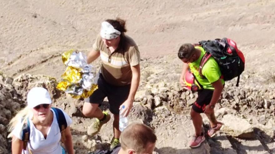 Los senderistas y un efectivo de rescate, ayer, en la subida de El Risco.