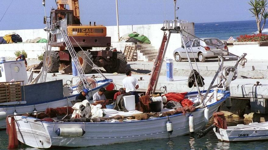 Pescadores trabajan en un barco en el puerto de La Bajadilla.