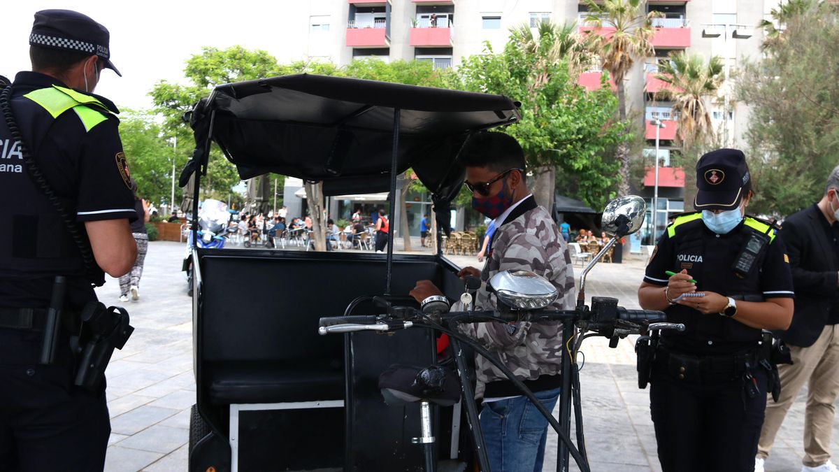 Dos agentes de la Guardia Urbana revisan los papeles de un conductor de bicitaxi