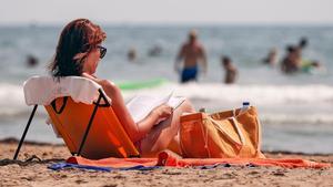 Una mujer toma el sol en una playa valenciana.