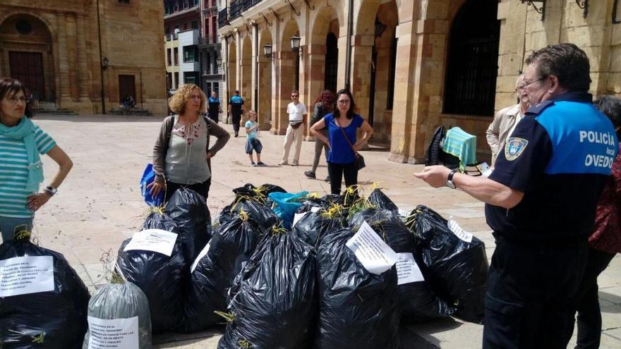 Los integrantes de la plataforma con las bolsas llenas de matojos con un agente de la Policía Local.