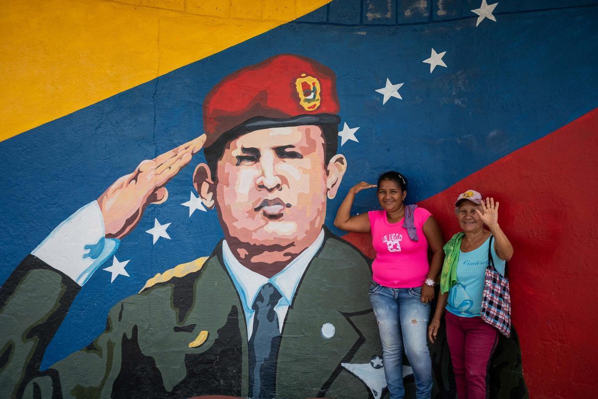 Dos mujeres posan para una fotografía junto a un mural de Hugo Chávez. Dos mujeres posan para una fotografía junto a un mural de Hugo Chávez.
