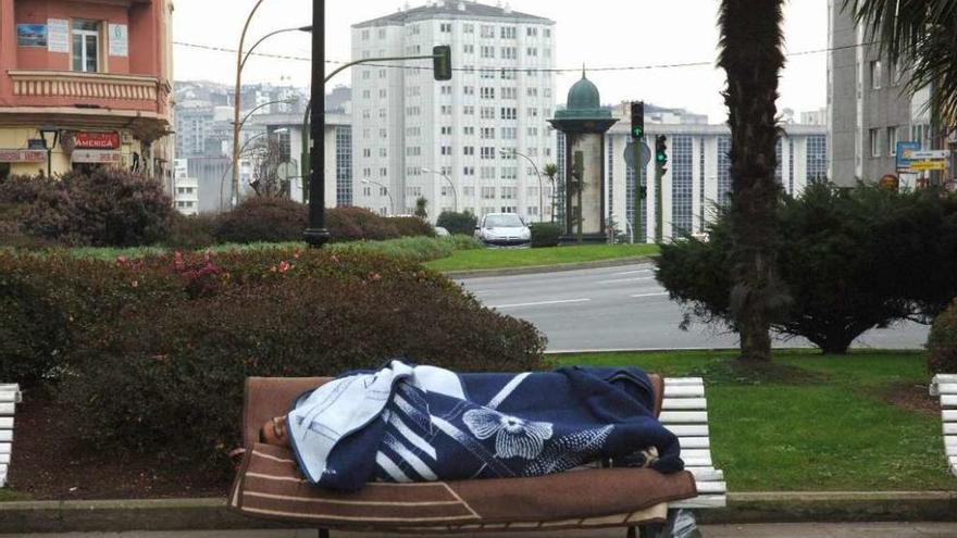 Un indigente duerme al aire libre en un banco de la plaza de San Cristóbal.