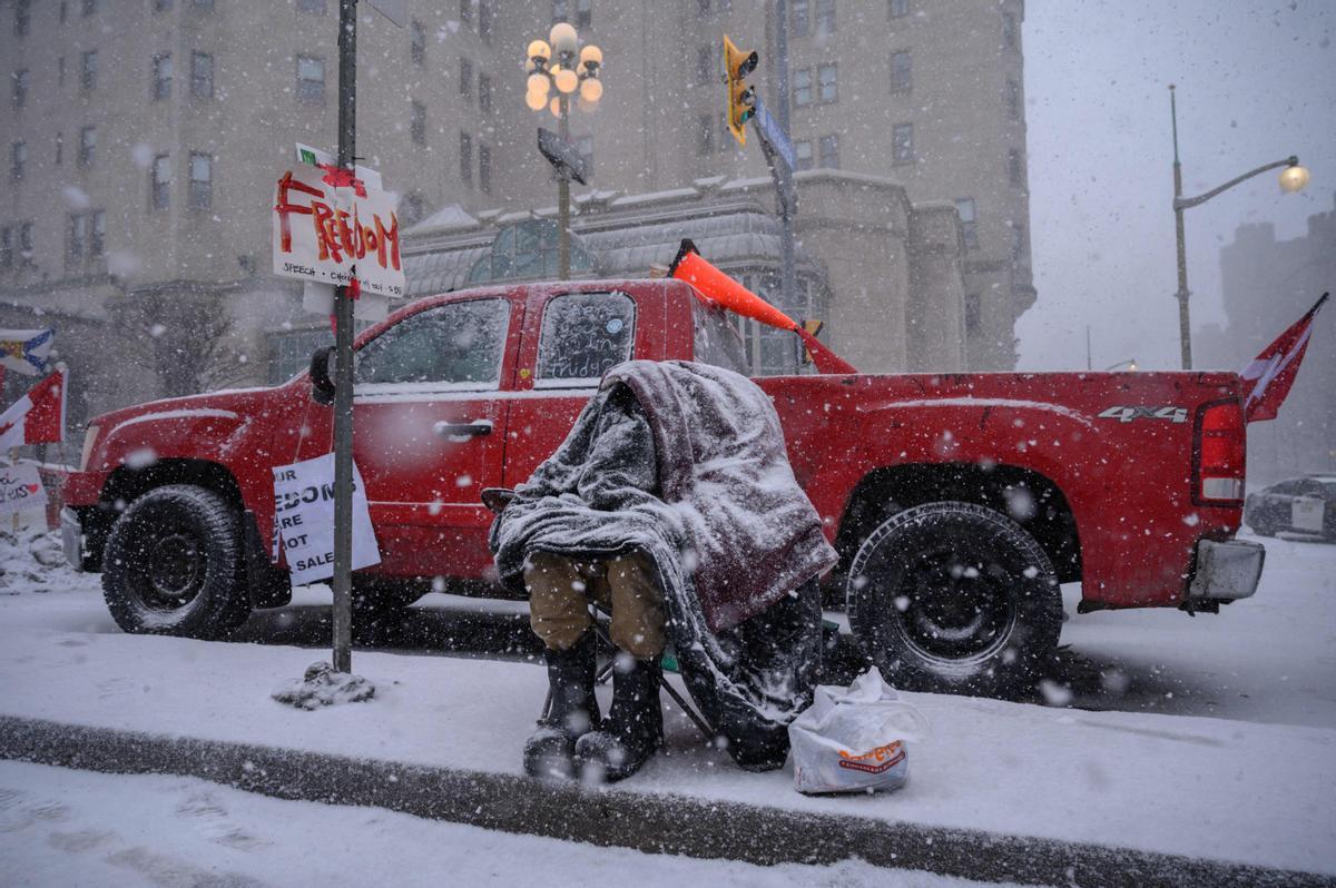 Un manifestante trata de abrigarse ante las bajas temperaturas que se están registrando en Ottawa, en otro día de protesta de los ’convoys de la libertad’.