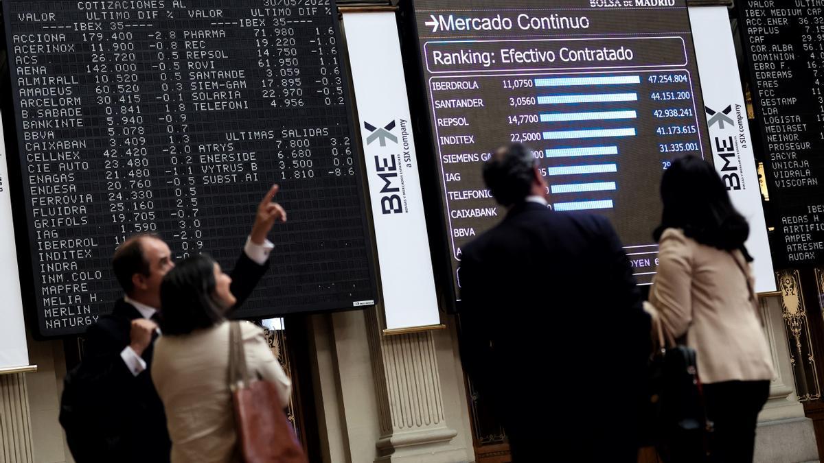 Cuatro personas frente a un panel de valores del Ibex.