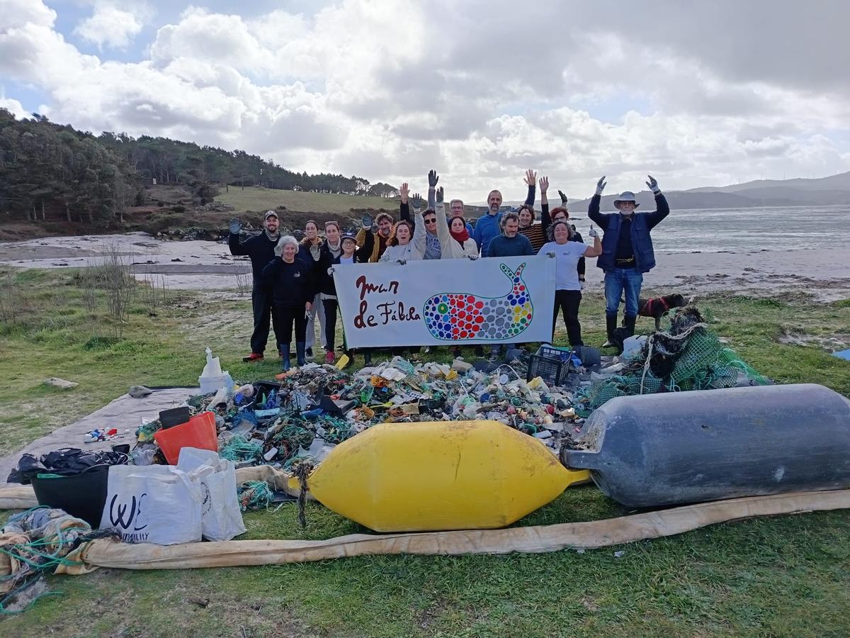Voluntarios participantes en la limpieza, junto a la basura recogida.