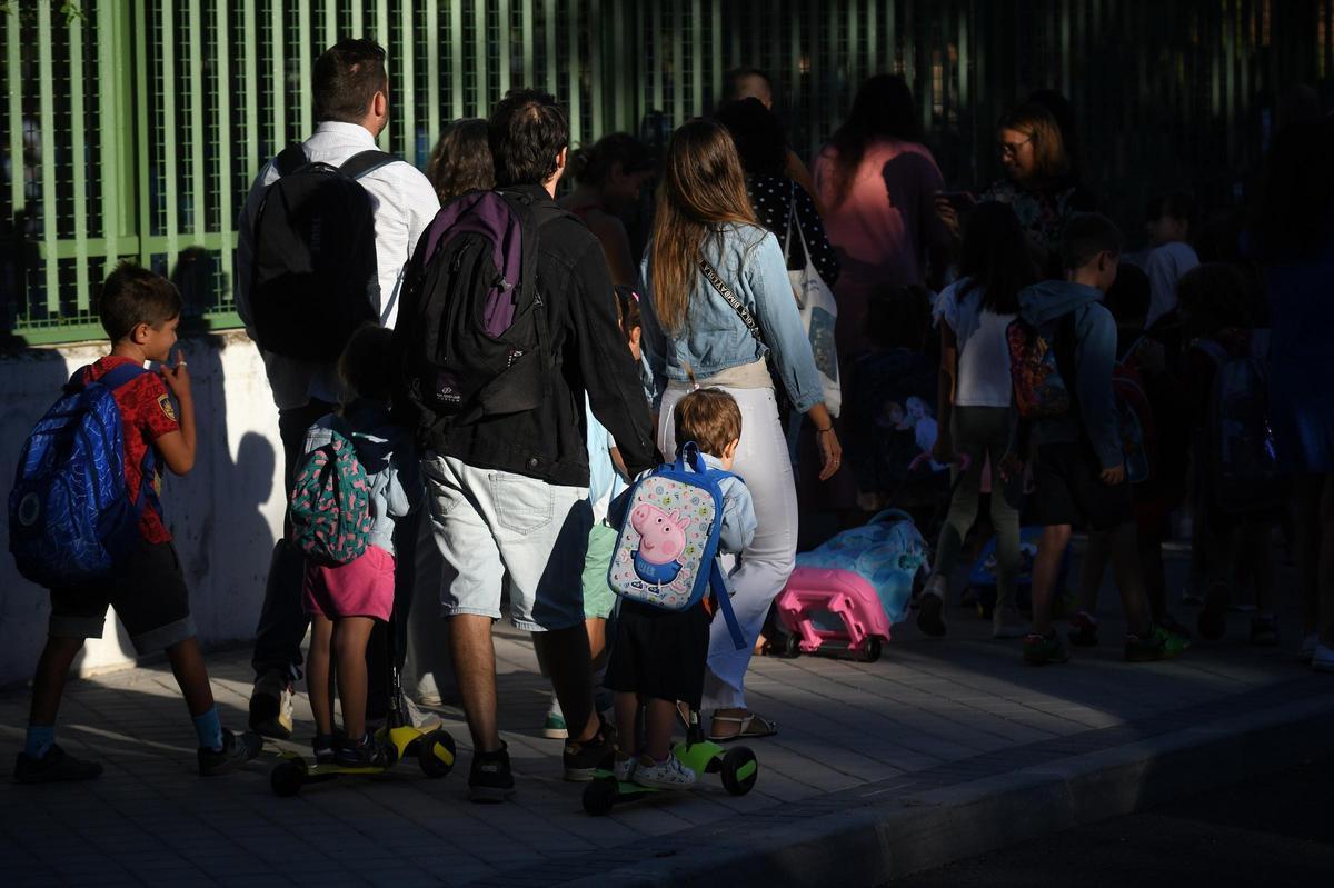 Niños y padres hacen cola para entrar al colegio el primer día.