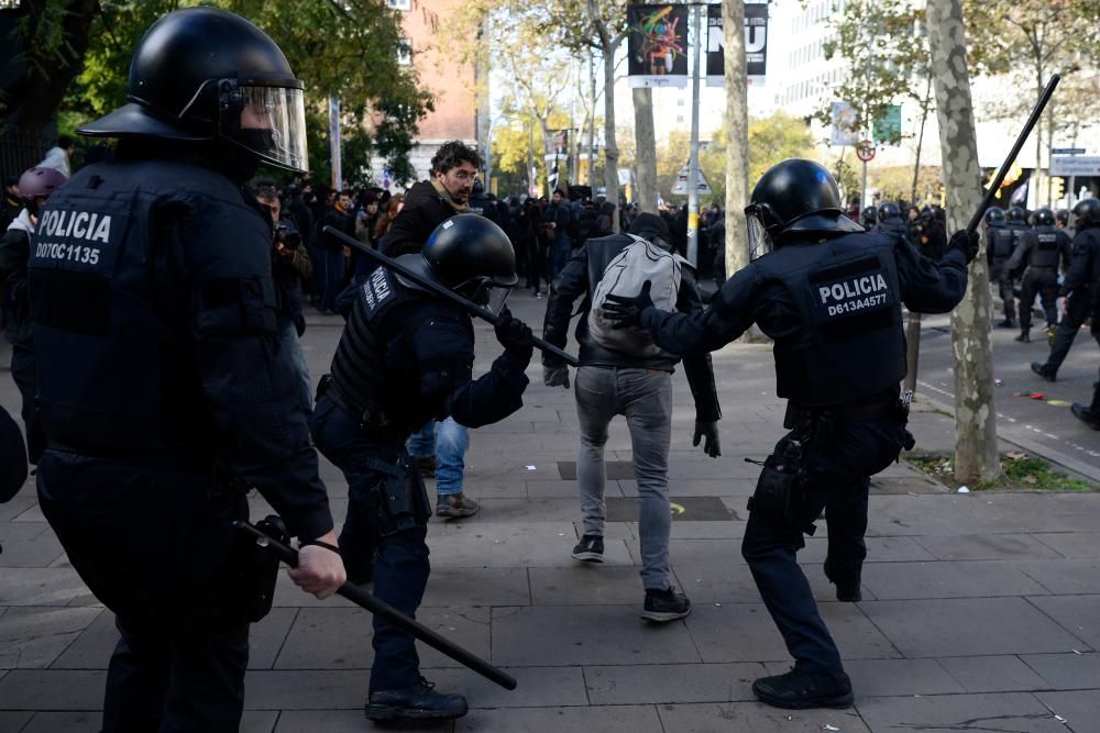 Police officers raise their batons as a protester runs for cover during a pro-independence demonstration in Barcelona on December 21, 2018 as the Spanish cabinet held a meeting in the city. - Catalan pro-independence groups blocked roads in the region to protest the meeting. The weekly cabinet meeting usually takes place in Madrid but the government decided to hold it in the Catalan capital as part of its efforts to reduce tensions in Catalonia, which last year made a failed attempt to break away from Spain. (Photo by Josep LAGO / AFP)