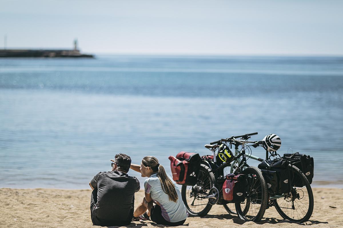 Dos ciclistes, a la platja gran de Sant Feliu de Guíxols.