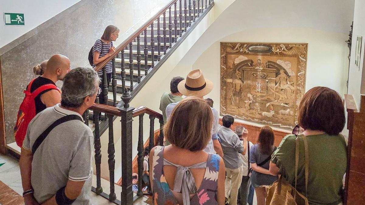 Los participantes en la visita, delante del tapiz de Antonio Juez en el Ayuntamiento de Badajoz.