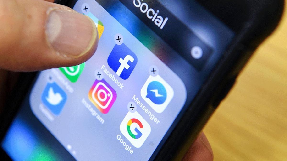 Un hombre organiza los iconos de varias redes sociales como Facebook, Instagram y Twitter en la pantalla de su móvil