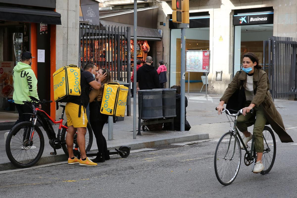 Beso en el Glovo, una pareja de repartidores de la empresa Glovo, se besa en frente de la Boquería.