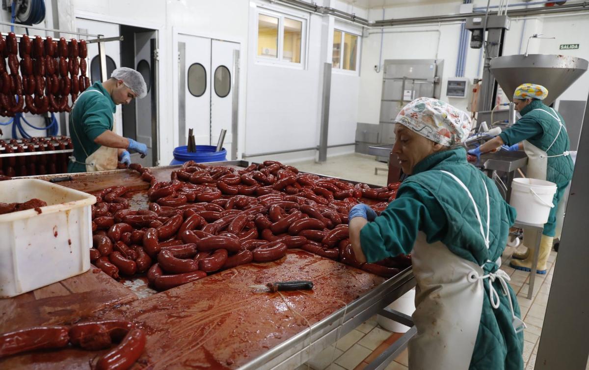 A la izquierda, personal de La Unión haciendo chorizos y los embutidos colgados en uno de los ahumaderos de la fábrica de Malleza. A la derecha, el interior de la caja de las conservas gourmet, con un manual de instrucciones para su consumo, y un muestrario de los productos de la empresa, con las latas en primer término.