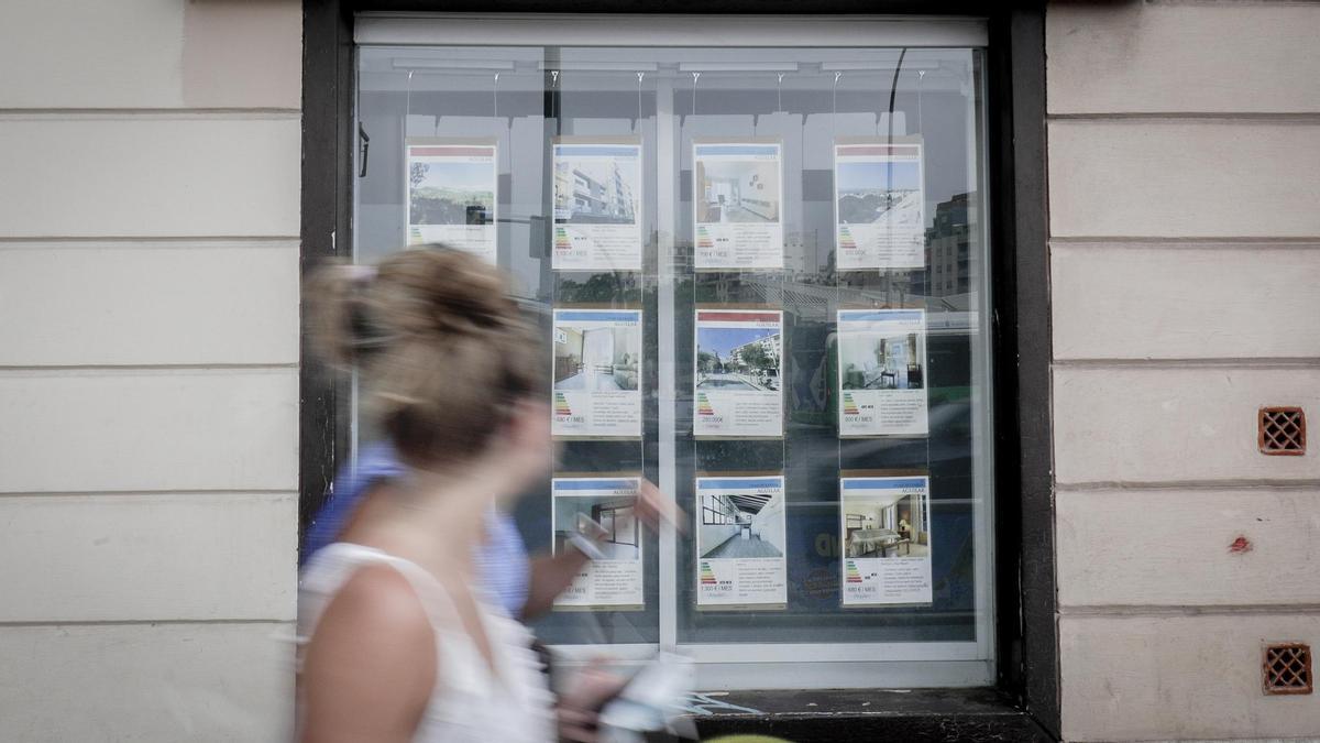 Una mujer pasa junto al escaparate de una inmobiliaria de Palma.