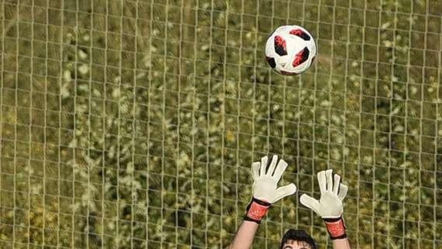 El meta del San Claudio Javi trata de hacerse con el balón.