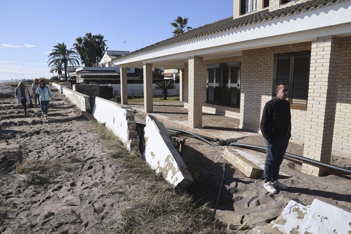 Un vecino camina por el chalé donde el mar derribó el vallado.
