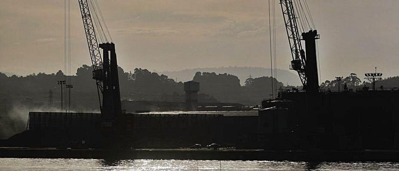 Dos grúas del muelle de Raíces vistas al atardecer desde la margen derecha de la ría. | Mara Villamuza