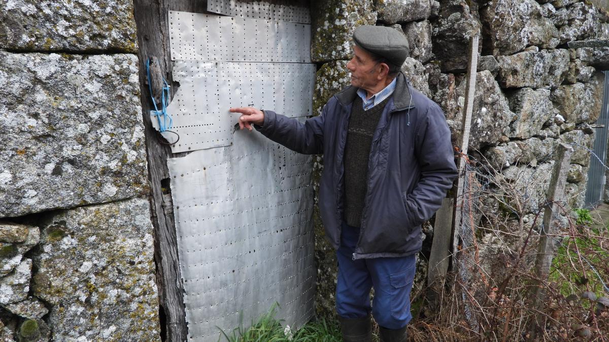 Celso muestra los restos del fuselaje del avión en una puerta en la aldea de Vilar. // FERNANDO CASANOVA