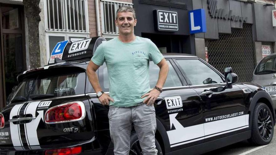 Iñaki Nistal posa junto a uno de sus vehículos ante su autoescuela en Oviedo.