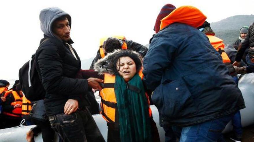 Una refugiada iraquí es ayudada al desembarcar de un &quot;dinghy&quot; en una playa de Lesbos.
