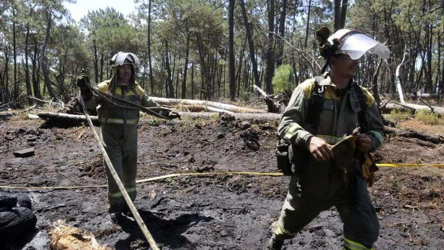 Dos operarios, en la zona quemada de la isla de Cortegada. // Noé Parga