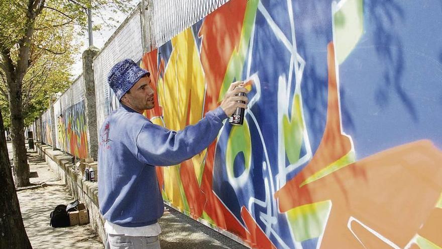 Un grafitero realizando su obra, ayer, en el paseo.  // Santos Álvarez