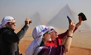 Turistes veneçolans contemplen l’eclipsi parcial del sol des de les piràmides de {Giza} . (AP {Photo}/Amr {Nabil})