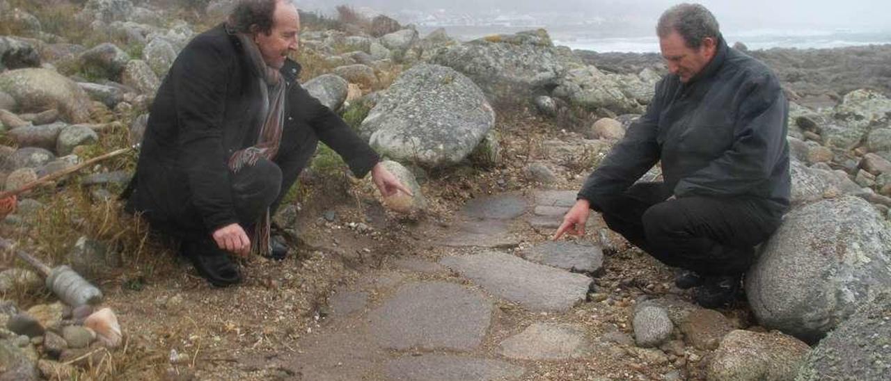 Javier Costas Goberna y Dino Vicente Refojos muestran, ayer, el posible fondo de un estanque salinero en el lugar de As Lagoas, en el límite entre Mougás y Viladesuso. // Ricardo Grobas