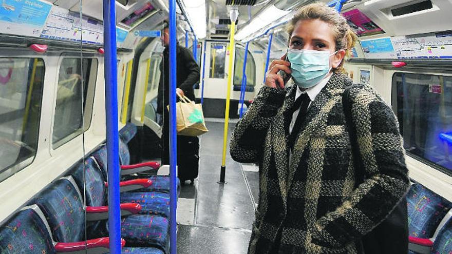 Una mujer con mascarilla habla por teléfono en el metro en Londres.