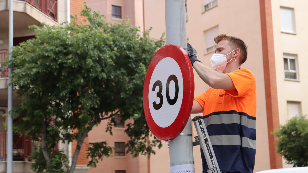 Un operario coloca una señal nueva de 30 km/h.