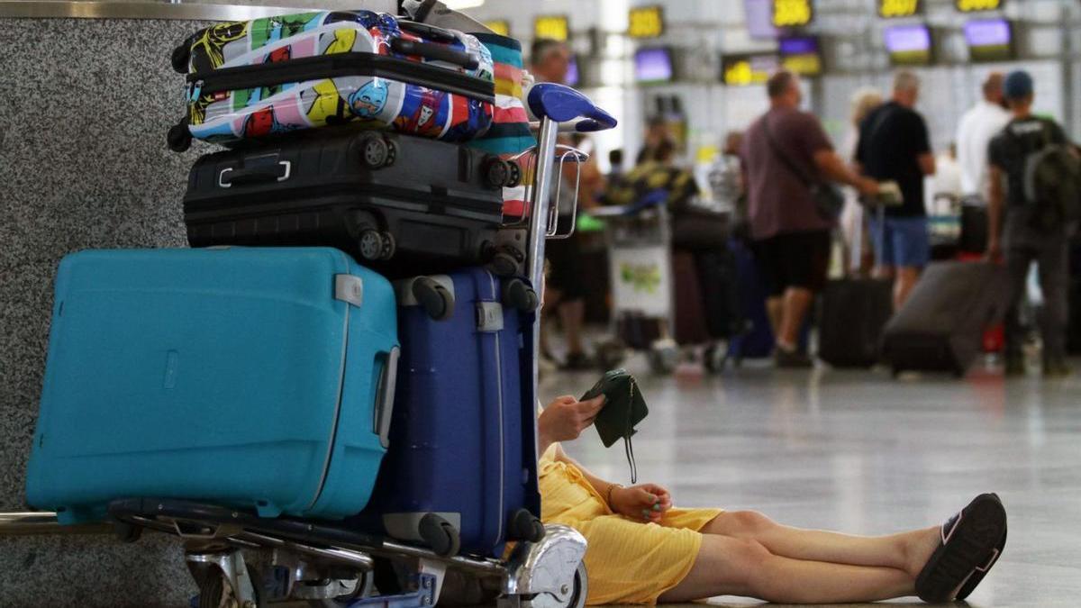 Una viajera espera con sus maletas en el aeropuerto de Málaga. | ENRIQUE SOLER