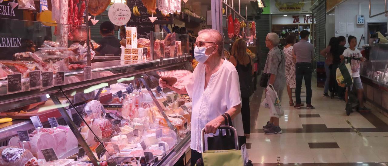 Una mujer de tercera edad acude al mercado a comprar.