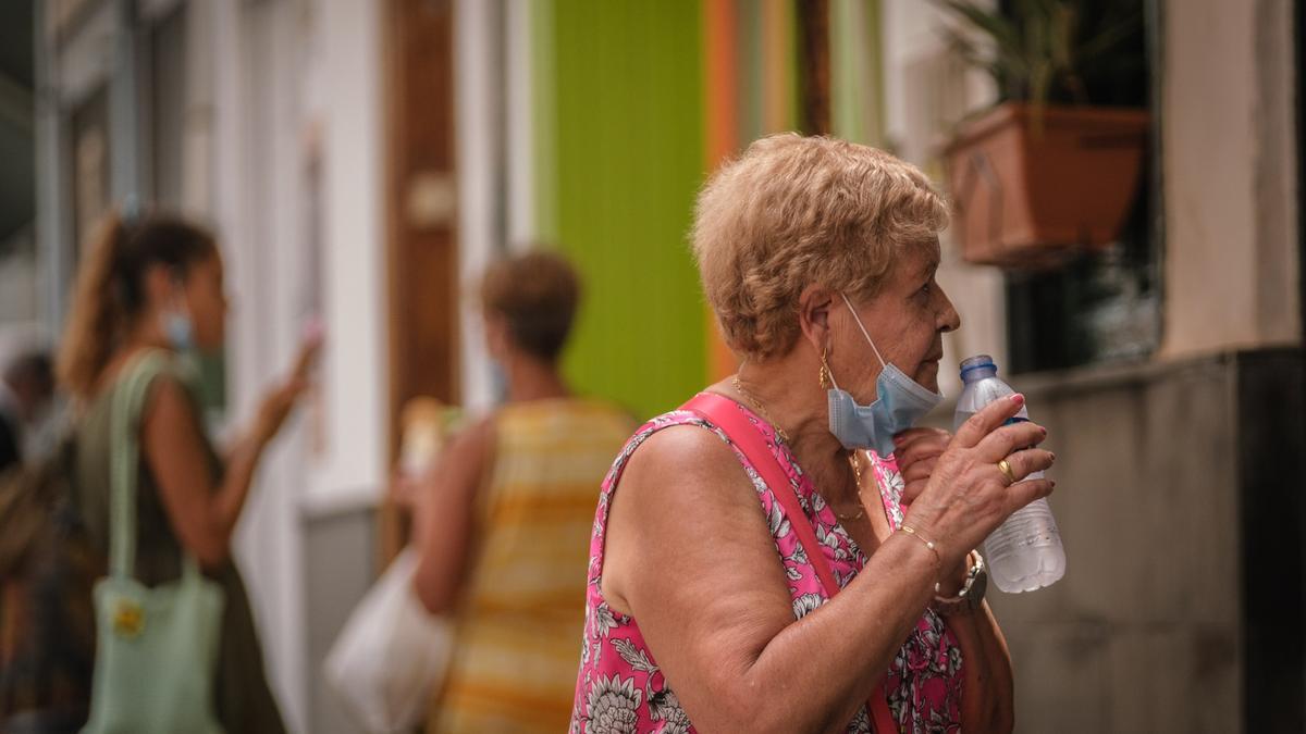 Una mujer bebe agua de una botella para refrescarse.