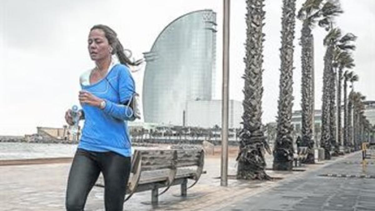 Esfuerzo controlado 8Una mujer corre por la playa de Sant Sebastià con el móvil en el brazo.