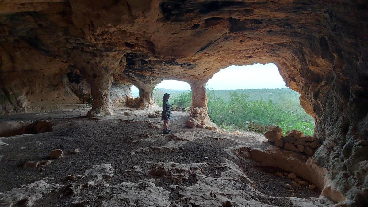 Vor ca. 2.500 Jahren bauten Menschen der talayotischen Kultur eine Naturhöhle zu einem 22 Meter langen, 15 Meter tiefen und bis zu 6 Meter hohen Raum aus, dessen ursprüngliche Verwendung bis heute nicht geklärt ist.