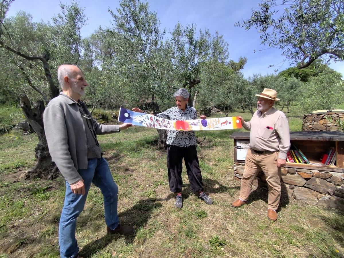 Oriol Homs, Roser Ros i Josep Maria Goñi desplegant un àlbum il·lustrat amb obra de la mateixa Ros.