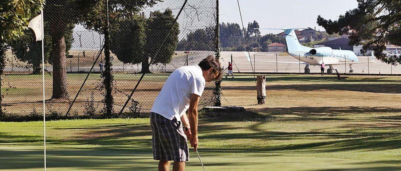 Un jugador de golf disputa un hoyo a escasos metros de las maniobras de un avión en pista.