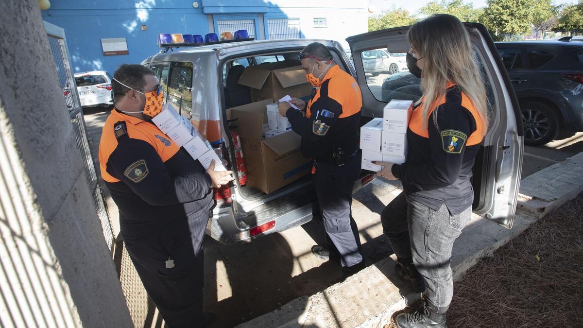 Voluntarios de Protección Civil reparten mascarillas en los colegios de Sagunt tras el confinamiento del covid.