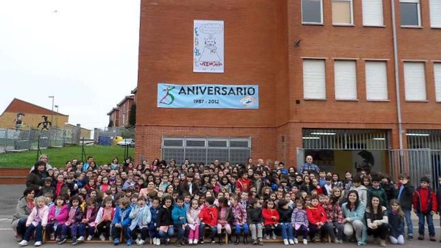 Los alumnos y profesores del Colegio Poeta Antón de Candás, en el patio, ante el cartel del 25.º aniversario.