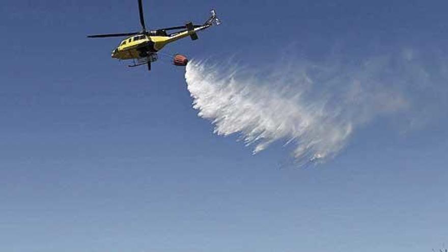 Un helicóptero intenta sofocar el incendio que se produjo el pasado mes de mayo en Bens.