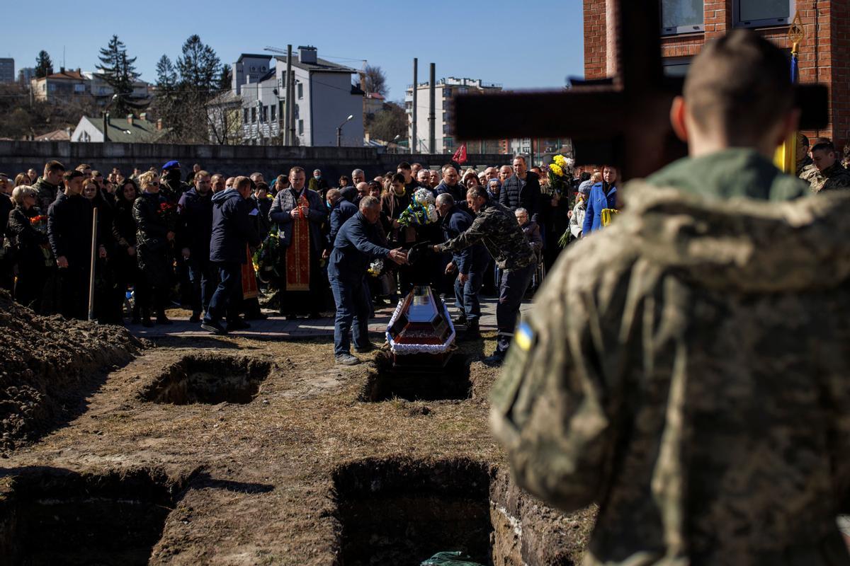 Los trabajadores del cementerio bajan el ataúd del soldado Roman Valkov, de 47 años, quien murió en una batalla en medio del ataque de Rusia a Ucrania, durante su funeral en el cementerio Lychakiv en Lviv, Ucrania.