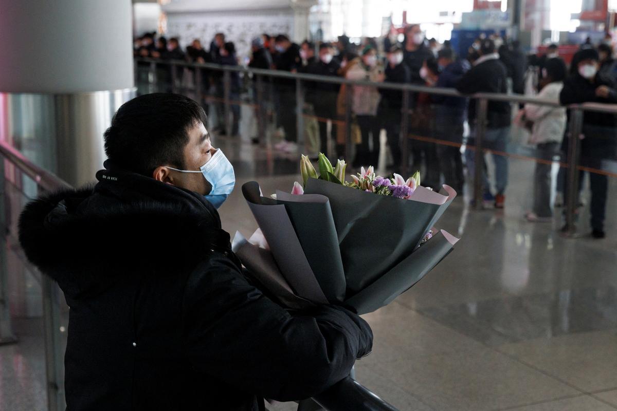 Un hombre sostiene flores mientras espera a un pasajero en la puerta de llegadas internacionales del Aeropuerto Internacional Capital de Beijing.