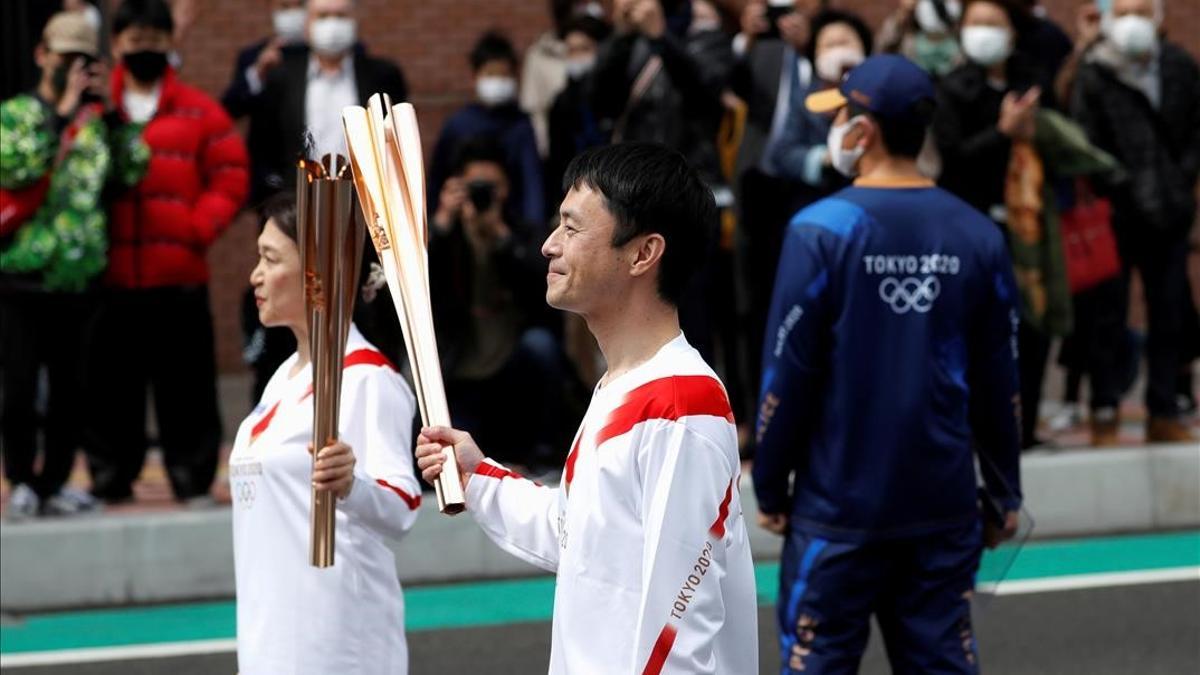 FILE PHOTO  Torchbearer Junko Ito hands the torch to the next torchbearer Yoshikazu Nishikata  during the Tokyo 2020 Olympic torch relay on the second day of the relay in Fukushima  Japan March 26  2021  REUTERS Issei Kato File Photo
