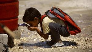 Un niño sirio, desplazado por la violencia del Estado Islámico, bebe agua antes de empezar el primer día de escuela en un campo para desplazados internos en Ain Issa, Siria. 