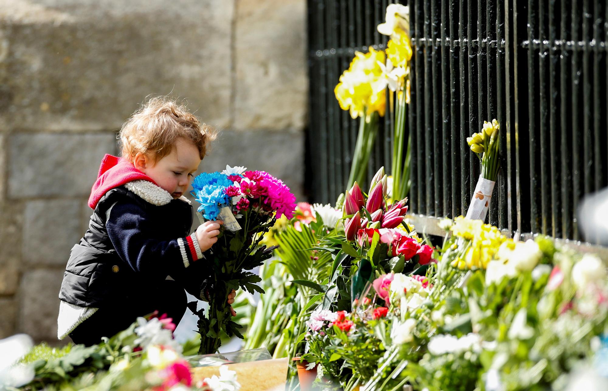 Un niño sostiene un ramo de flores frente al castillo de Windsor tras la muerte del príncipe Felipe, marido de la reina Isabel. Reuters