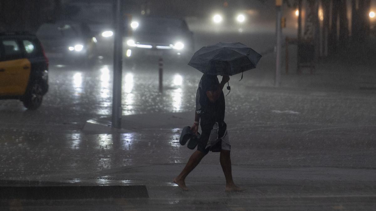 Tormenta de verano por la tarde en la ciudad de Barcelona que ha obligado a los transeúntes a protegerse de la lluvia con plásticos y paraguas. Fotografía de Jordi Cotrina