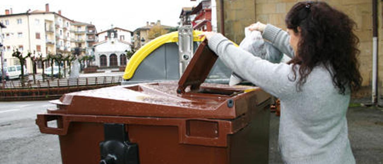 Una vecina deposita basura orgánica en un contenedor marrón.